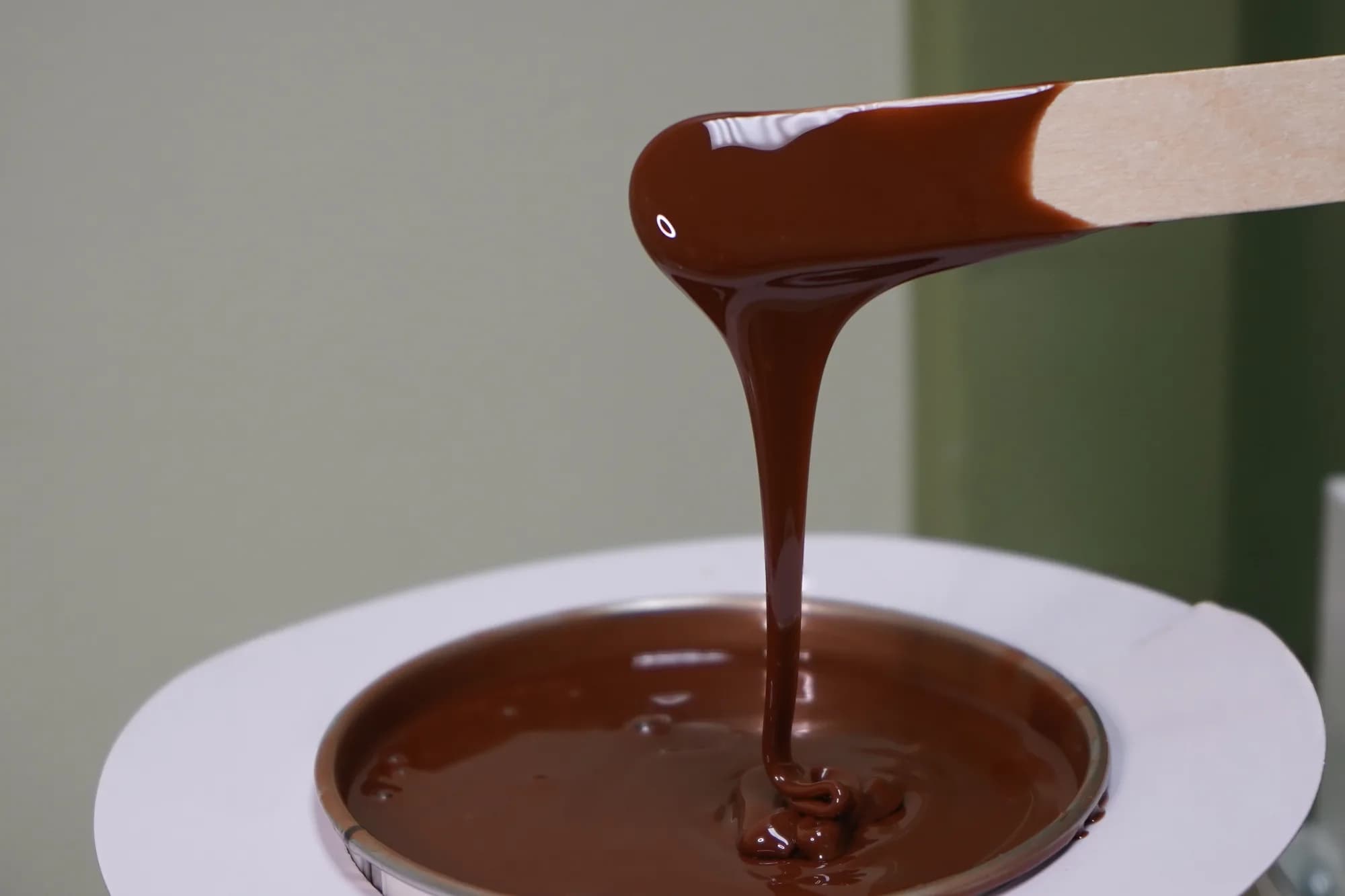 Warm chocolate wax on a wooden spatula